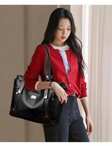 Détail du sac cabas en cuir grainé noir avec fermeture éclair latérale et logo métallique