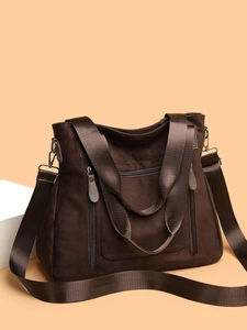 Detail view of large dark brown tote bag with multiple zippers and adjustable wide strap