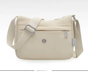 Detailed shot of beige waterproof nylon crossbody bag showing the front zipper pocket