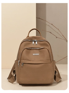 Détail du sac à dos marron en nylon avec texture tissée, zips métalliques et poches latérales