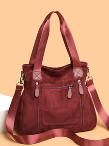Detail of burgundy suede tote bag featuring high-density nylon straps and front zipper pocket