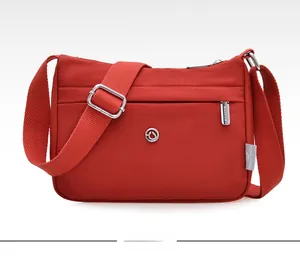 Detailed front view of red nylon crossbody bag showing zippers and metallic logo