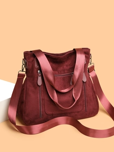 Detail of wine red faux suede tote bag featuring wide nylon straps and decorative zippers