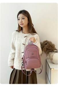 Close-up of dusty pink nylon travel backpack with premium metal logo and compartments