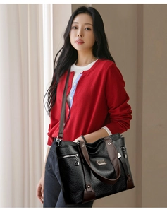 Détail d'un grand sac cabas noir avec lanières marron porté en bandoulière par un modèle