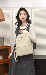 Sac à dos en nylon tissé beige avec poignée et poche avant présenté par un mannequin