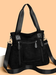 Detail of black large tote bag featuring three front zip pockets and wide nylon strap