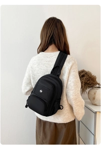 Close-up of black multifunctional sling bag with multiple zippers and side mesh pocket