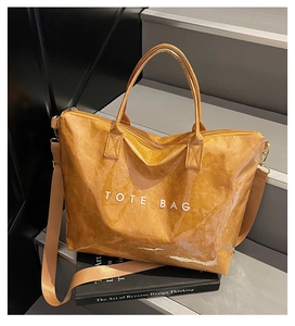 Detail of yellow Tyvek tote bag with transparent PVC overlay and bold white TOTE BAG text