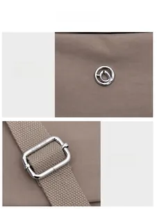 Detail of silver brand logo and adjustable metal buckle on waterproof nylon shoulder bag