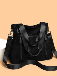 Macro detail of the black suede tote bag showing zipper pockets and hardware textures