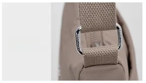 Detailed close-up of premium silver metal hardware on a brown nylon shoulder bag