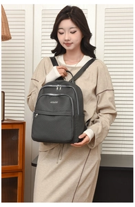 Détail du sac à dos en nylon gris avec doubles fermetures éclair et plaque logo en métal