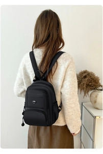 Rear view of model wearing a black waterproof nylon backpack with adjustable straps