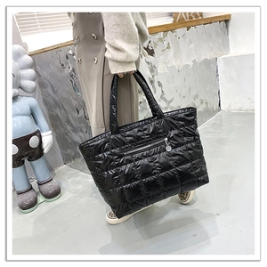 Detailed shot of a black quilted puffer tote bag with zipper pocket and padded straps