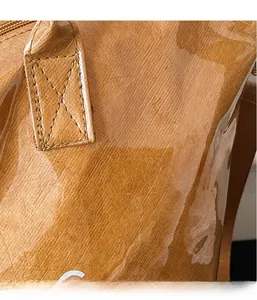 Detail of brown glossy crinkled fabric tote with reinforced stitching and white logo