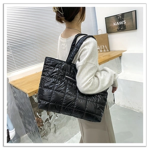 Detail view of large black quilted tote bag with soft padding and side zipper