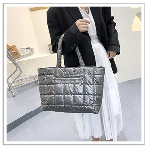 Detail of silver quilted tote bag showing metallic finish and front zipper pocket
