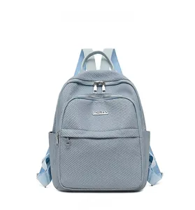 Détail frontal du sac à dos en nylon bleu clair avec zips argentés et logo JINGPIN