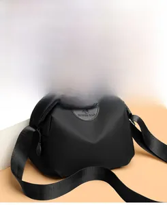 Close-up of black Oxford cloth bag showing SOSIDI logo patch and woven shoulder straps