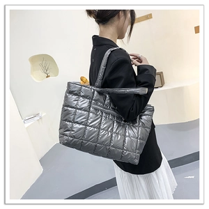 Detailed view of silver quilted tote bag featuring metallic texture and square stitching