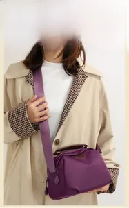 Detail of purple nylon crossbody bag with wide shoulder strap and dark brown leather handle