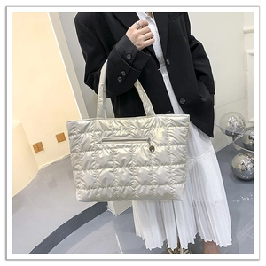 Silver quilted puffer tote bag detail with zip pocket on woman in black blazer