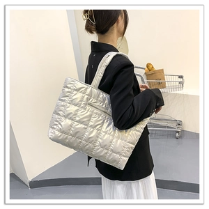 Detailed side view of silver quilted tote bag showing hidden zipper and puffy texture