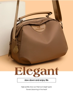 Detail of a brown oxford fabric shoulder bag showing the logo and side charm