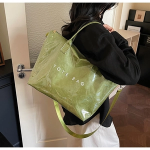 Detail of green glossy tote bag with white text and durable nylon shoulder strap