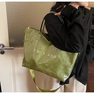 Detail of green patent leather tote bag with white TOTE BAG print and adjustable strap