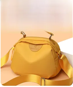 Close-up of vibrant yellow Oxford cloth handbag featuring leather logo and sturdy straps