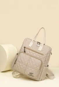 Detailed close-up of beige quilted nylon backpack featuring dual front zippers and kangaroo logo