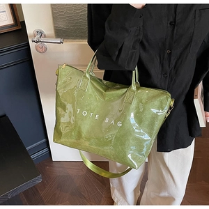 Close-up of green crinkled tote bag with TOTE BAG print and adjustable shoulder strap