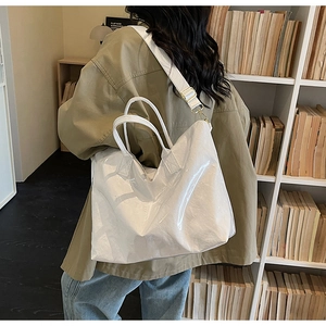 Detail of white Tyvek tote bag with metal buckle and textured surface on a model