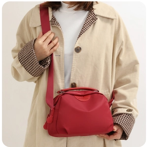 Detailed view of red nylon crossbody bag with adjustable shoulder strap and logo