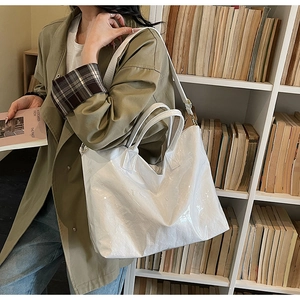 White Tyvek tote bag with embossed TO BAG letters shown on model in a library setting
