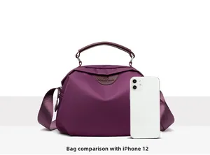 Size comparison between the purple nylon crossbody bag and an iPhone 12 for scale