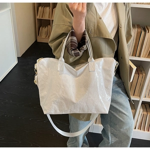 White Tyvek tote bag with embossed TOTE BAG text shown on an indoor model
