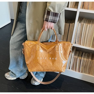 Macro detail of camel brown glossy tote bag with dual handles and wide shoulder strap
