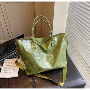 Detail of green wrinkled tote bag featuring a glossy texture and white text on a desk