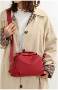 Close-up of red Oxford fabric crossbody bag with adjustable strap and logo detail