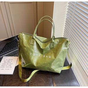Detail view of a green textured tote bag with TOTE BAG print on a desk setup