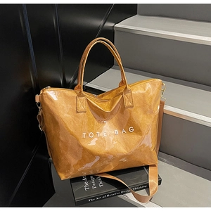 Detail view of large caramel brown tote bag with white TOTE BAG print and adjustable strap