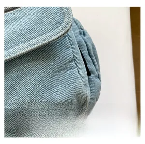 Close-up of light blue denim fabric texture and precise stitching on a shoulder bag