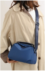 Detailed view of blue nylon crossbody bag texture with adjustable wide strap on model