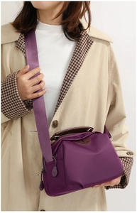 Detail of purple nylon crossbody bag with fabric strap and premium leather handle