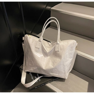 Detail of white Dupont paper tote bag with TOTE BAG relief and wide fabric strap