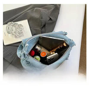 Detail view of denim shoulder bag showing spacious interior with tablet and daily essentials