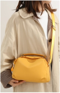 Detail view of yellow nylon crossbody bag with leather patch and adjustable wide strap